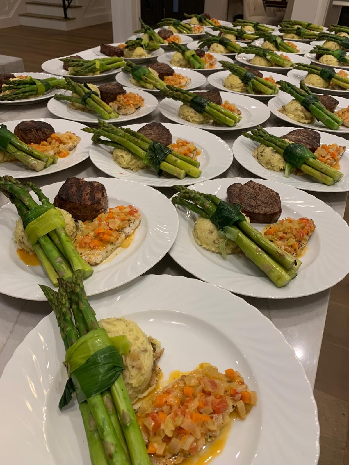 Rows of plated filet, mashed potatoes and asparagus ready for service